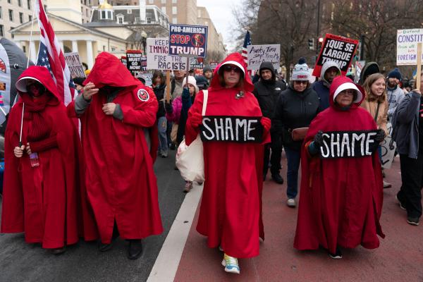 Handmaids hold their signs as they march near the White House at Trump Must Go Now rally, December 13, 2025.