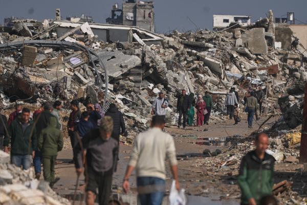 Palestinians walk by buildings destroyed during Israeli air and ground operations in Gaza City, December 17, 2025.