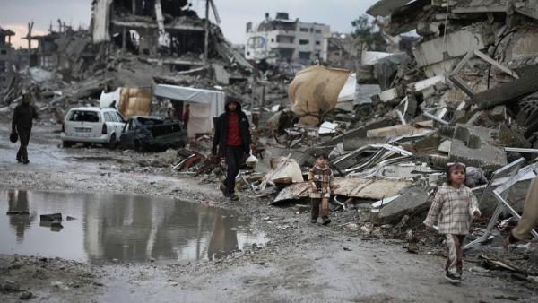 Palestinians walk through the rubble amid stormy weather in Gaza City, December 11, 2025.