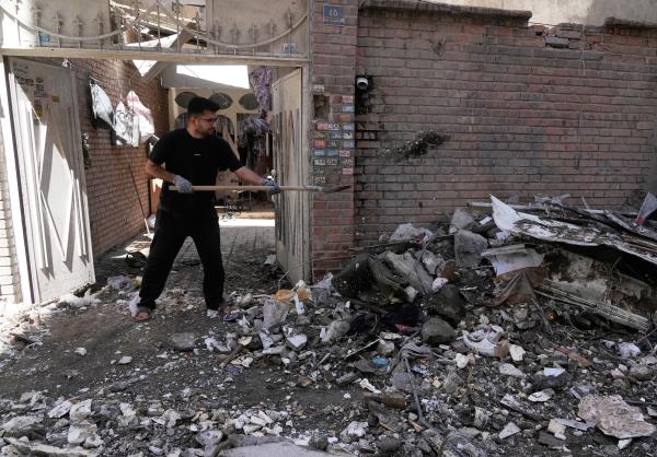 Iranian clears debris in a residential building hit by a U.S.-Israeli strike in Tehran, Friday, March 27, 2026.