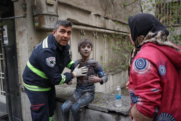 A first responder assists an injured boy following a U.S.-Israeli airstrike on a residential building in Tehran, Iran, March 28, 2026.