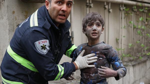 A first responder assists an injured boy following a U.S.-Israeli airstrike on a residential building in Tehran, Iran, March 28, 2026.