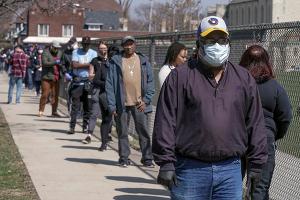 Milwaukee voters wait in line to cast ballots, while social distancing, at Washington High School, April 7, 2020.