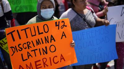 A woman holds a sign that reads "Title 42 discriminates against Latin America," during a protest of people waiting in Mexico as they hope to apply for asylum, 
