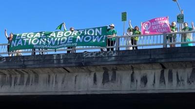 Holding banner Legal Abortion Nationwide Now on overpass