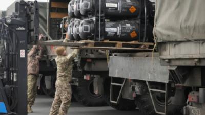 Ukrainian servicemen load weaponry from the U.S. into trucks.