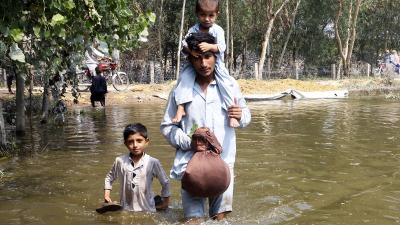 Pakistan father with two children stand in flood waters