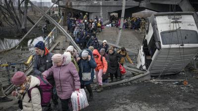 March 5, 2022, Ukraine: People cross path under a bridge destroyed by Russian airstrike.