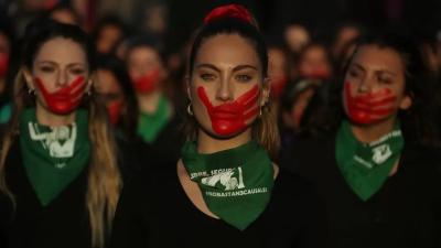 Women in Argentina protest with purple hands painted on their face