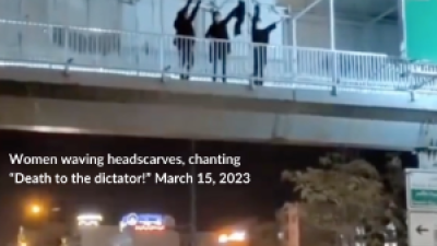 Three women on a pedestrian bridge over a highway in Tehran, waving their headscarves and chanting “Death to the dictator!” March 15, 2023 (Twitter: @1500tasvir)