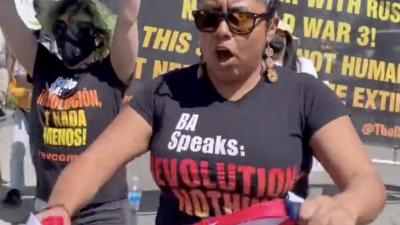 Woman with Revolution Nothing Less t-shirt tearing up U.S. flag