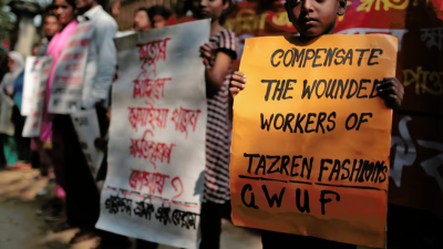 Relatives of victims of the Tazreen factory fire demonstrate, November 24, 2014. The center sign reads, “Sumaya Khatun, a victim of Tazreen Fashions fire—where is compensation?”