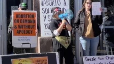 Protesters with signs: Break the Chains, Unleash the Fury of Women as a Mighty Force for Revolution