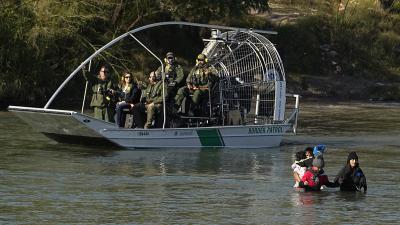 Migrants crossing the Rio Grande at Eagle Pass, Texas, are watched by border patrol agents, January 3, 2024.