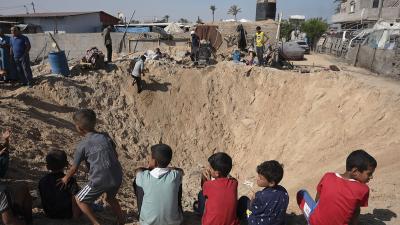 Children gather around a huge crater in refugee camp in Khan Younis from Israeli airstrike, June 21, 2024.
