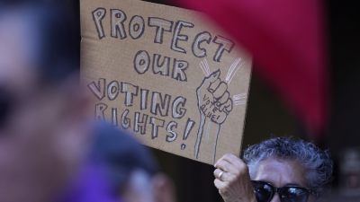 "Protect our voting rights," A sign at a news conference proesting raids by Texas Attorney General Ken Paxton, Monday, Aug. 26, 2024