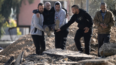 Palestinians evacuate from the Jenin refugee camp in the West Bank carrying an elderly man over rubble, January 23, 2025.