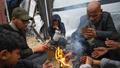 Displaced Palestinians warm by a fire at a camp near Rafah, Gaza, February 24, 2025.