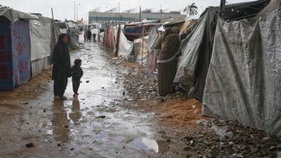  Mother and child examine damage from flooding at a tent camp in the central Gaza Strip, November 14, 2025.