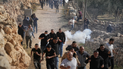 Palestinians run away from tear gas shot by Israeli forces during a protest against land confiscation in Tarkumiya, West Bank, November 28, 2025.