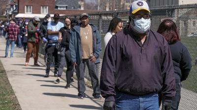 Milwaukee voters wait in line to cast ballots, while social distancing, at Washington High School, April 7, 2020.