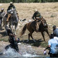 Mounted Texas Border Patrol on horseback whip and yell at Haitian immigrants who crossed the Rio Grande River from Mexico into the U.S. 