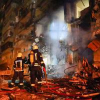 Firemen in front of burning building in Kyiv, Ukraine destroyed by Russian fire attack