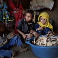 Children sit around moldy bread at shelter in Yemen.