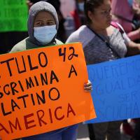 A woman holds a sign that reads "Title 42 discriminates against Latin America," during a protest of people waiting in Mexico as they hope to apply for asylum, 