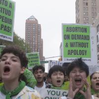 Young women marching with signs Abortion on Demand and Without Apology in English and Spanish