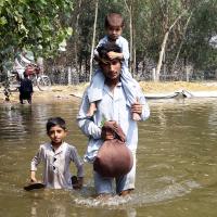 Pakistan father with two children stand in flood waters
