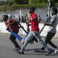 Haitian protesters carry a woman wounded in police fire, October 10, 2022.