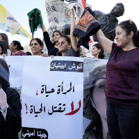 Kurdish women hold headscarfs high to protest murder of Mahsa Amini.