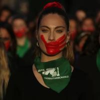 Women in Argentina protest with purple hands painted on their face