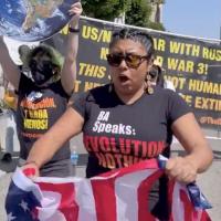 Woman with Revolution Nothing Less t-shirt tearing up U.S. flag