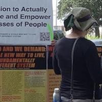 Two people discussing display including "Education to Actually Educate and Empower the Masses of People"