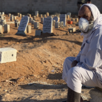 A grieving man sits by graves of flash flood victims in Derna, Libya, Friday, Sept. 15, 2023.