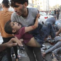 Palestinian carries a boy injured from Israeli airstrike outside the entrance of the al-Shifa hospital in Gaza City, November 3, 2023.
