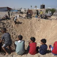 Children gather around a huge crater in refugee camp in Khan Younis from Israeli airstrike, June 21, 2024.