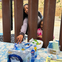 A woman seeking asylum reaches for a bottle of water after crossing the border with a child, June 5, 2024, in San Diego.