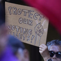 "Protect our voting rights," A sign at a news conference proesting raids by Texas Attorney General Ken Paxton, Monday, Aug. 26, 2024