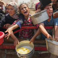 Palestinians struggle to get donated food at a community kitche in in Gaza City, August 16, 2025.