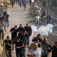 Palestinians run away from tear gas shot by Israeli forces during a protest against land confiscation in Tarkumiya, West Bank, November 28, 2025.