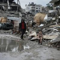 Palestinians walk through the rubble amid stormy weather in Gaza City, December 11, 2025.