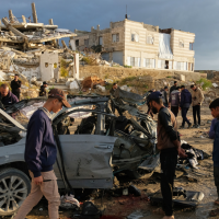 Palestinians look at a destroyed car following an Israeli strike in Gaza City, December 13, 2025