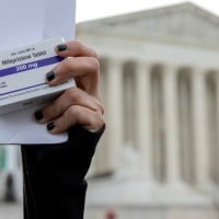 An abortion-rights activist holds a box of mifepristone pills as demonstrators from both anti-abortion and abortion-rights groups rally outside the Supreme Court in Washington, March 26, 2024.